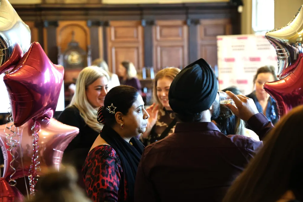 Guests talking among pink and silver star balloons in the wood-panelled hall of the Guildhall, High Wycombe, at the HWBIDCo Business Awards